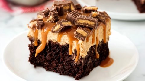 Sliced chocolate peanut butter poke cake with caramel drizzle in a plate.