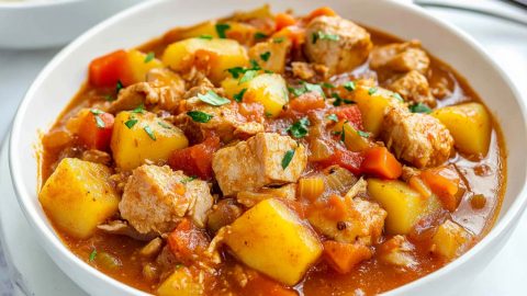 Pork stew with tomatoes, carrots, and potatoes served in a white bowl.