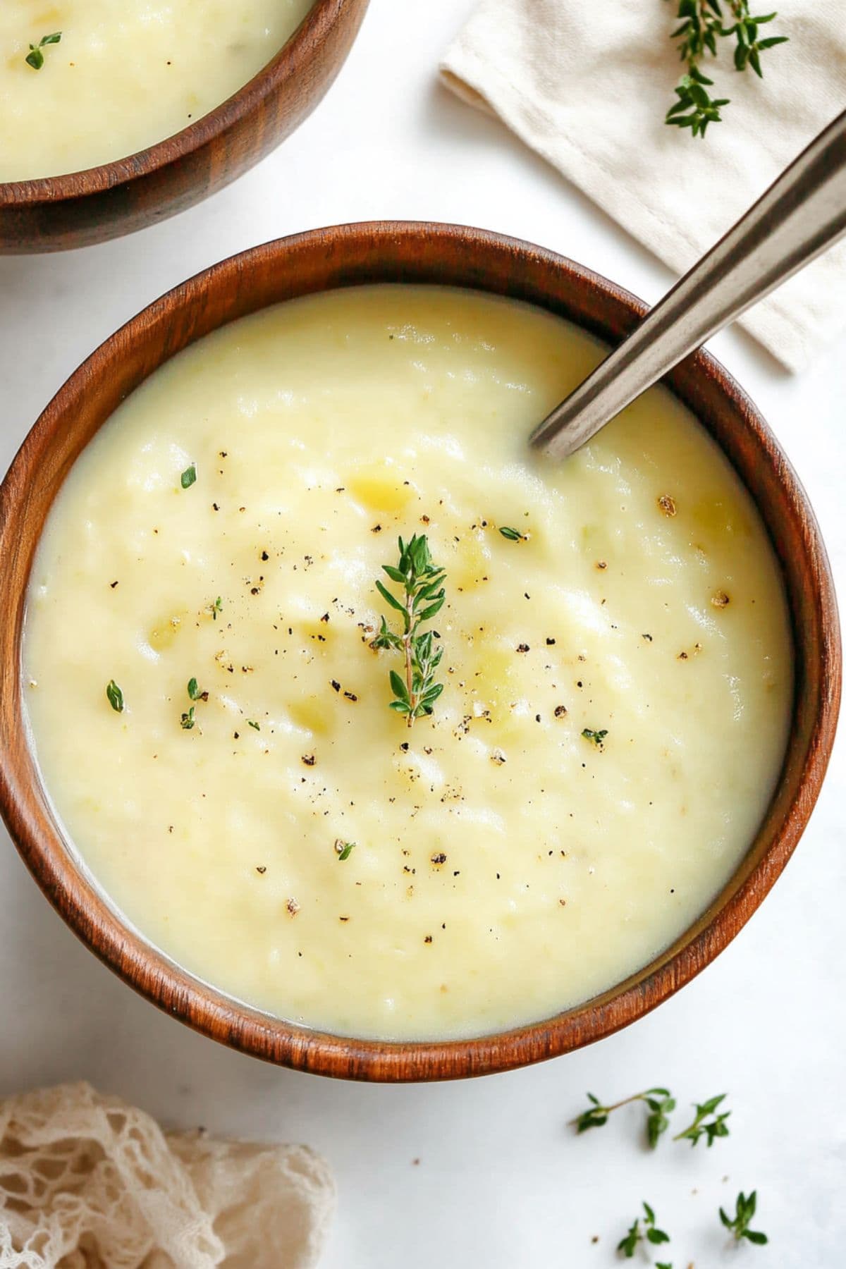 Top view of wooden bowl with serving of creamy potato leek soup.