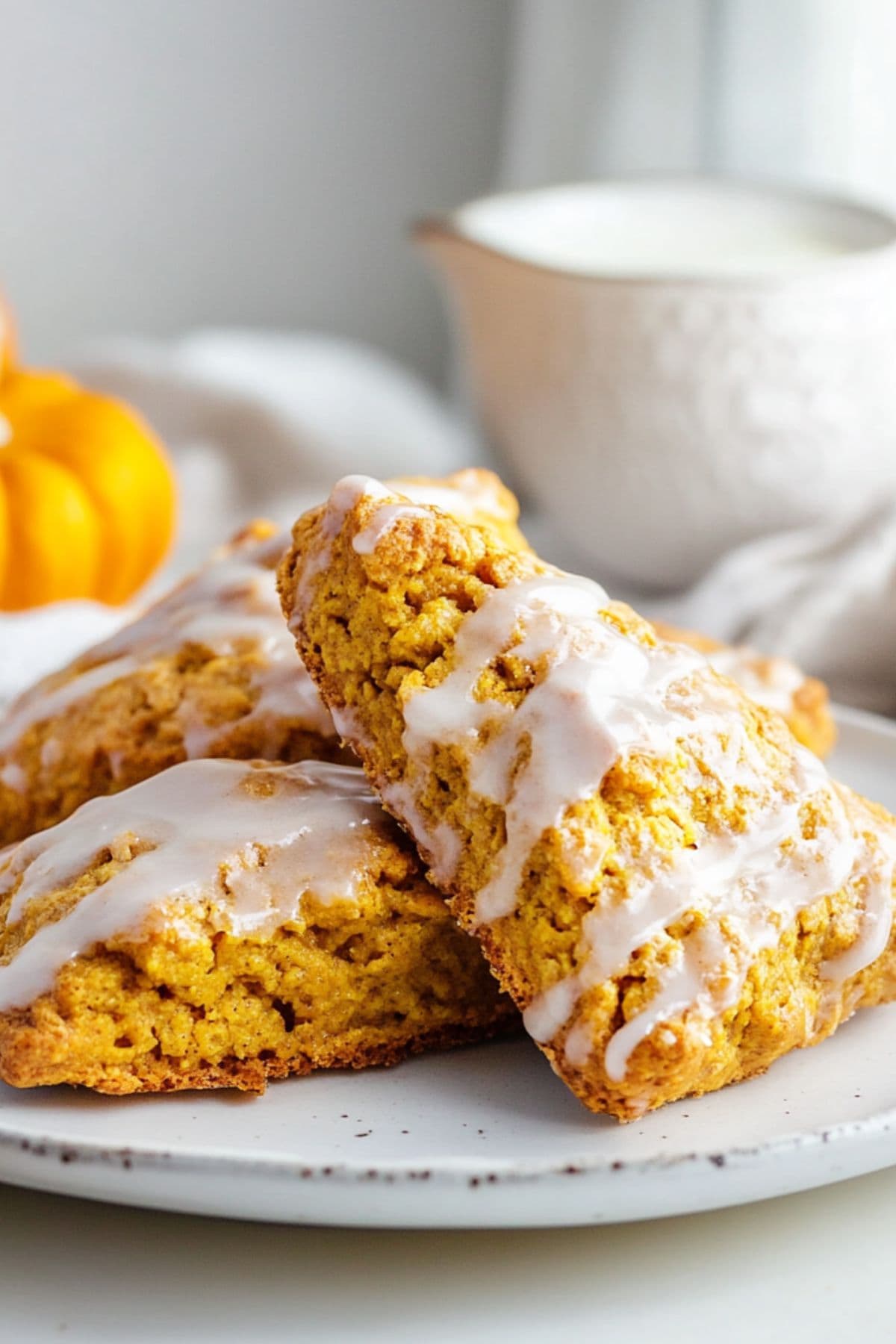 Pieces of pumpkins scones drizzled with white sugar served in a white plate.