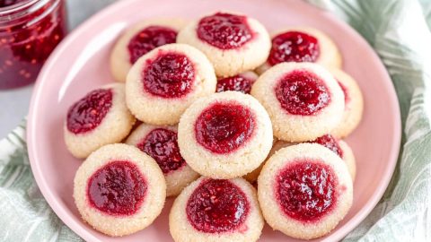 Plate of homemade thumbprint cookies filled with vibrant red jam.