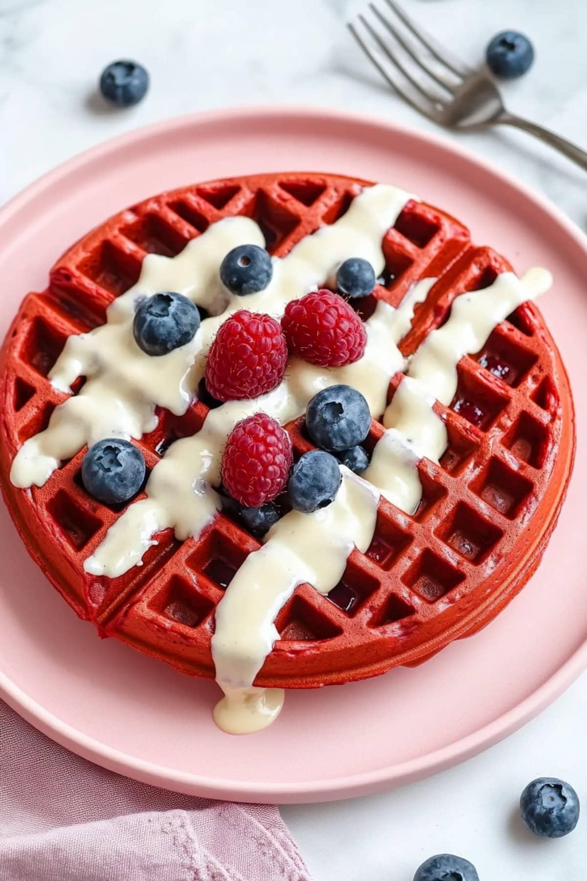 Homemade red velvet waffles with raspberries, blueberries and cream cheese glaze, top view