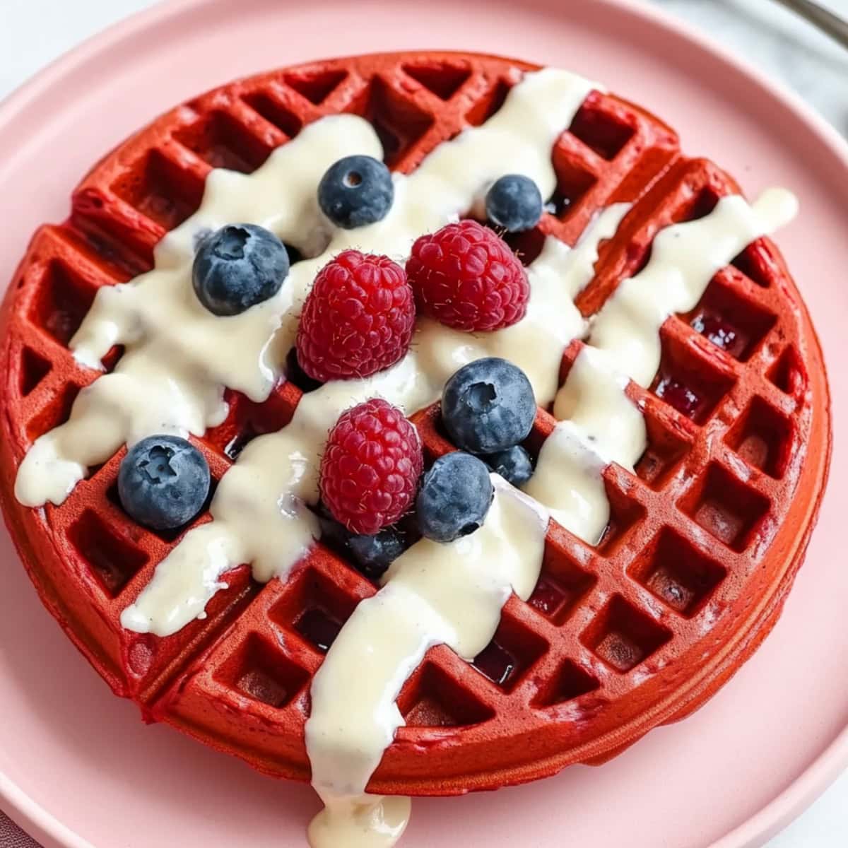 Red velvet waffle served with cream cheese glaze with fresh berries, top view