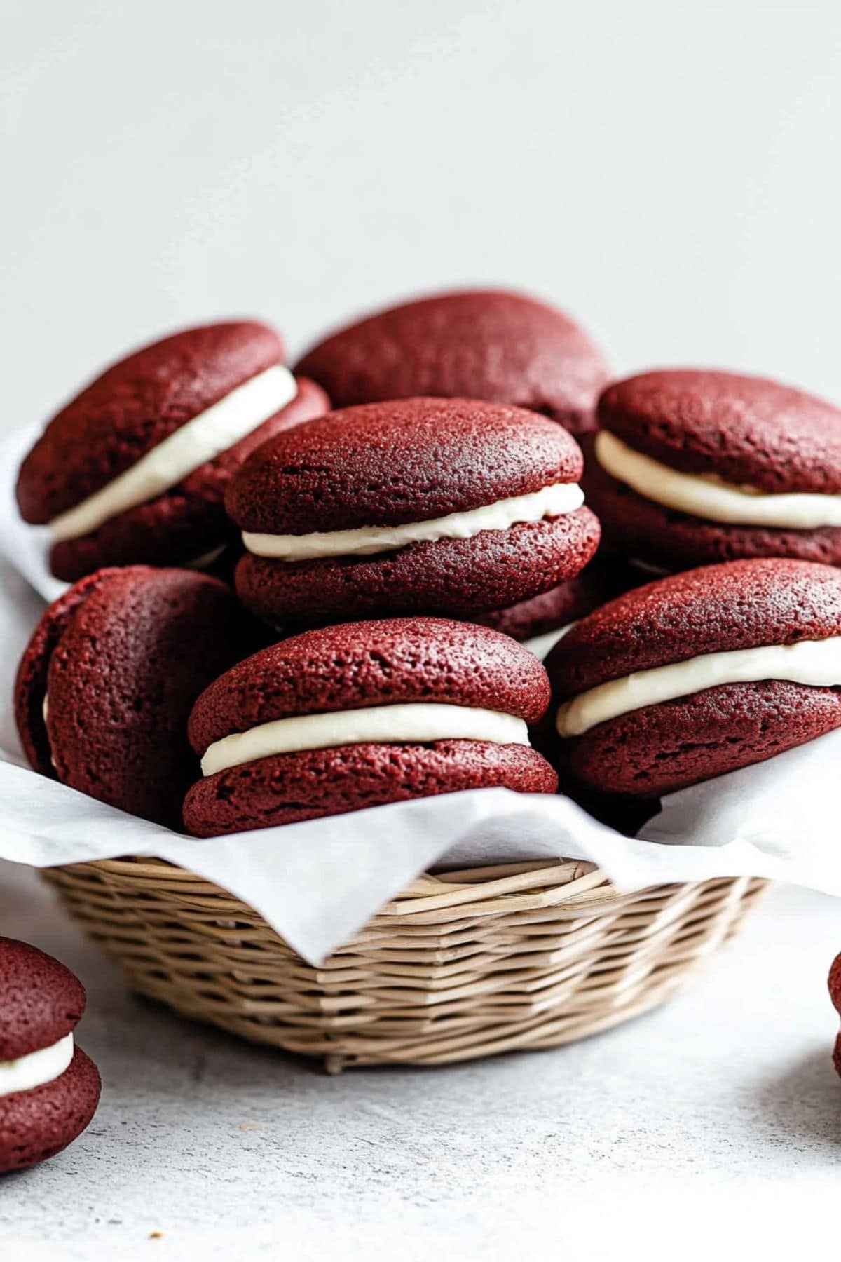 Bunch of red velvet whoopie pies arranged in a woven basket.