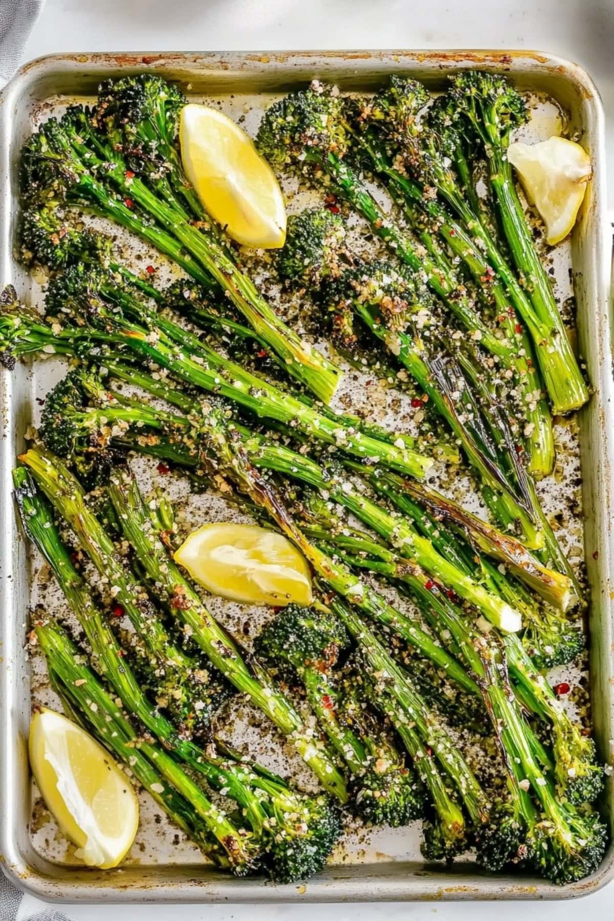 Homemade roasted broccolini with red pepper flakes and lemon wedges.