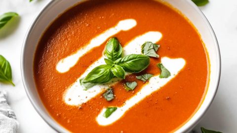 Smooth roasted red pepper soup on a white marble counter top.