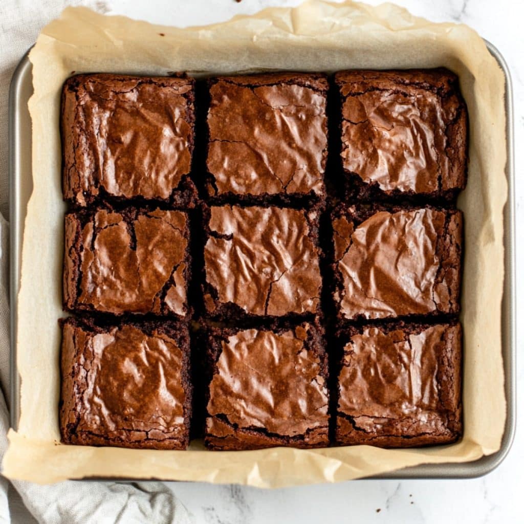 Brownies sliced in a baking pan with parchment paper, top view