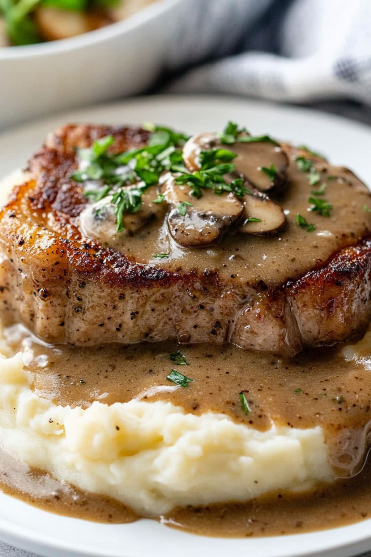 Porkchop served on top of mashed potato with gravy and mushroom on top.