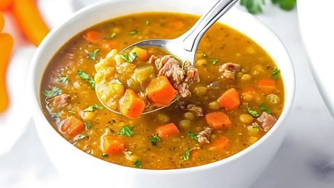 Spilt pea soup in a white bowl scooped with a spoon.