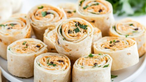 Bunch of sliced taco pinwheels in a white plate.