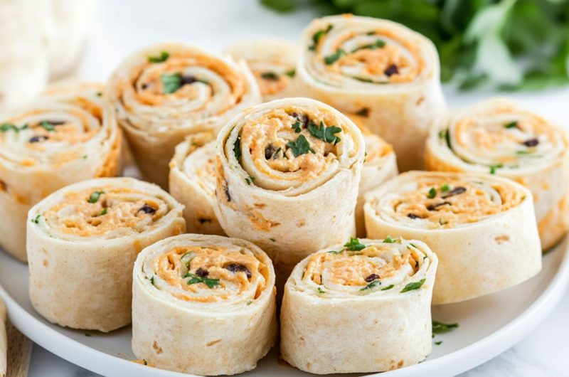 Bunch of sliced taco pinwheels in a white plate.