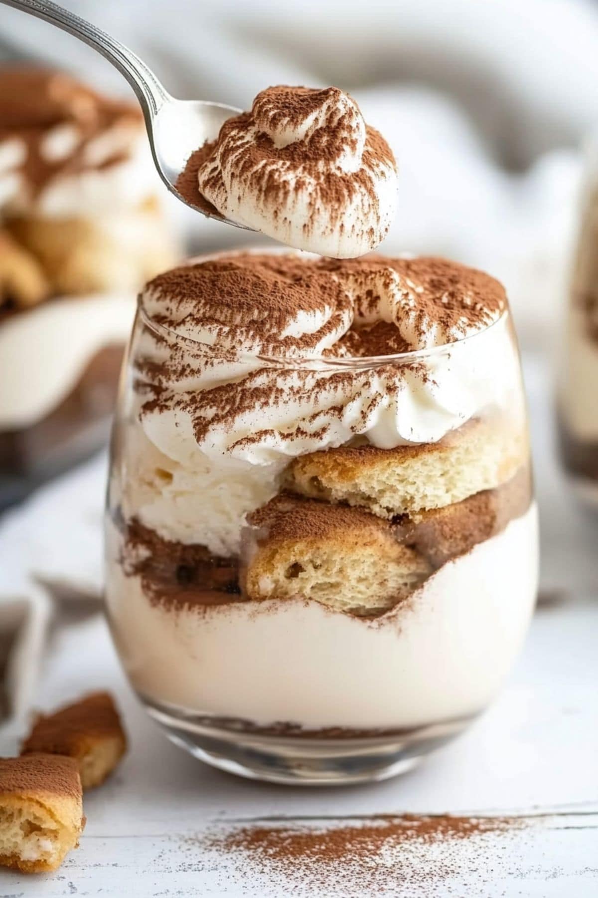 Tiramisu in a single serving glass dusted with cocoa powder on top.