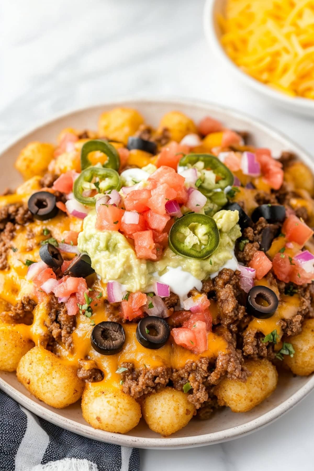 A serving of crunchy totchos with melted cheese, black beans, sour cream and pico de gallo.