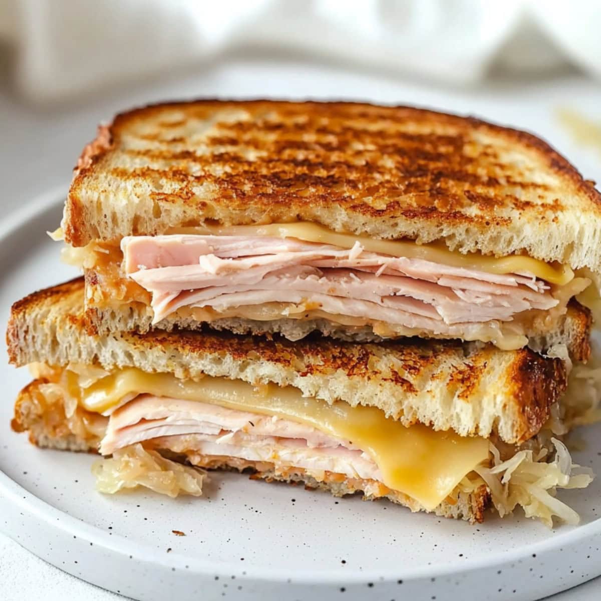 Sliced in half turkey Reuben sandwich served in plate.