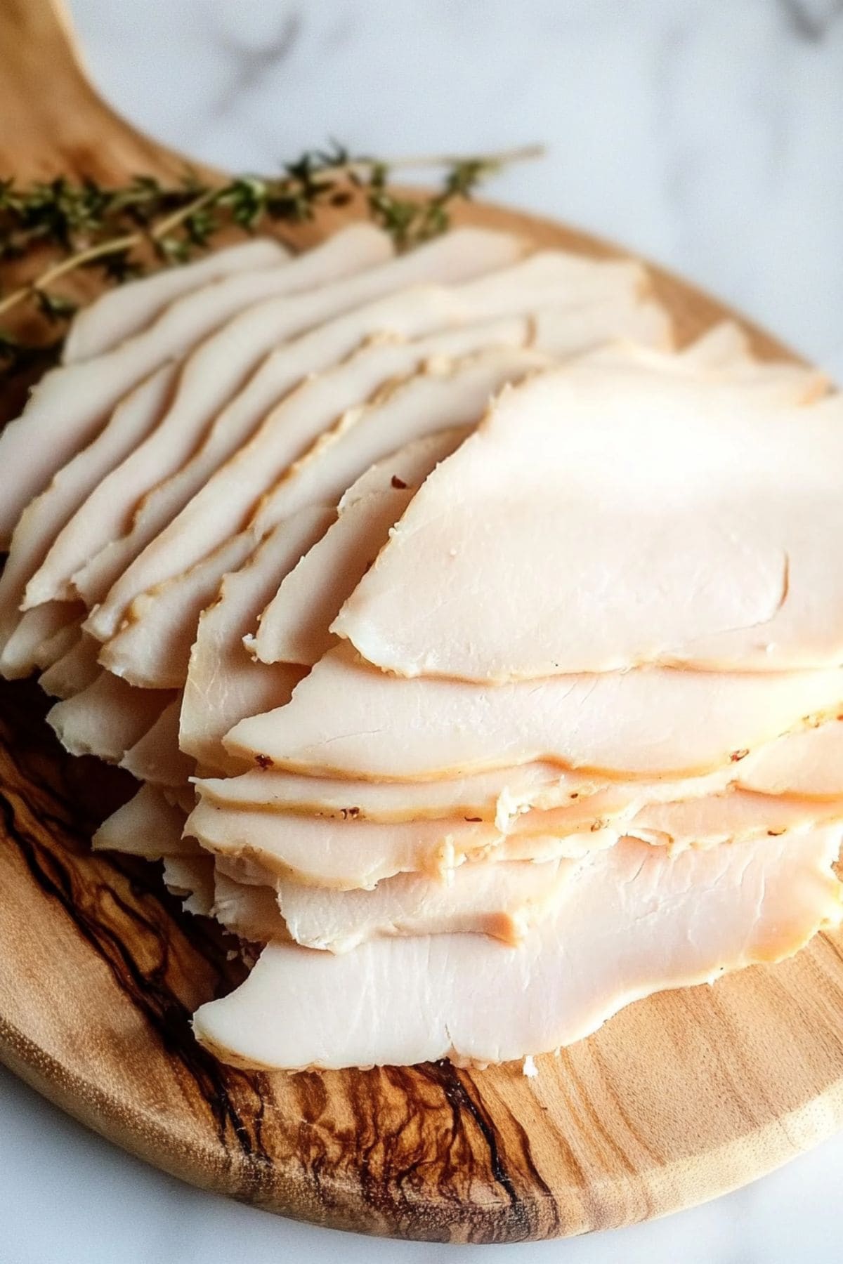 Slices of turkey breast sitting on a wooden board.