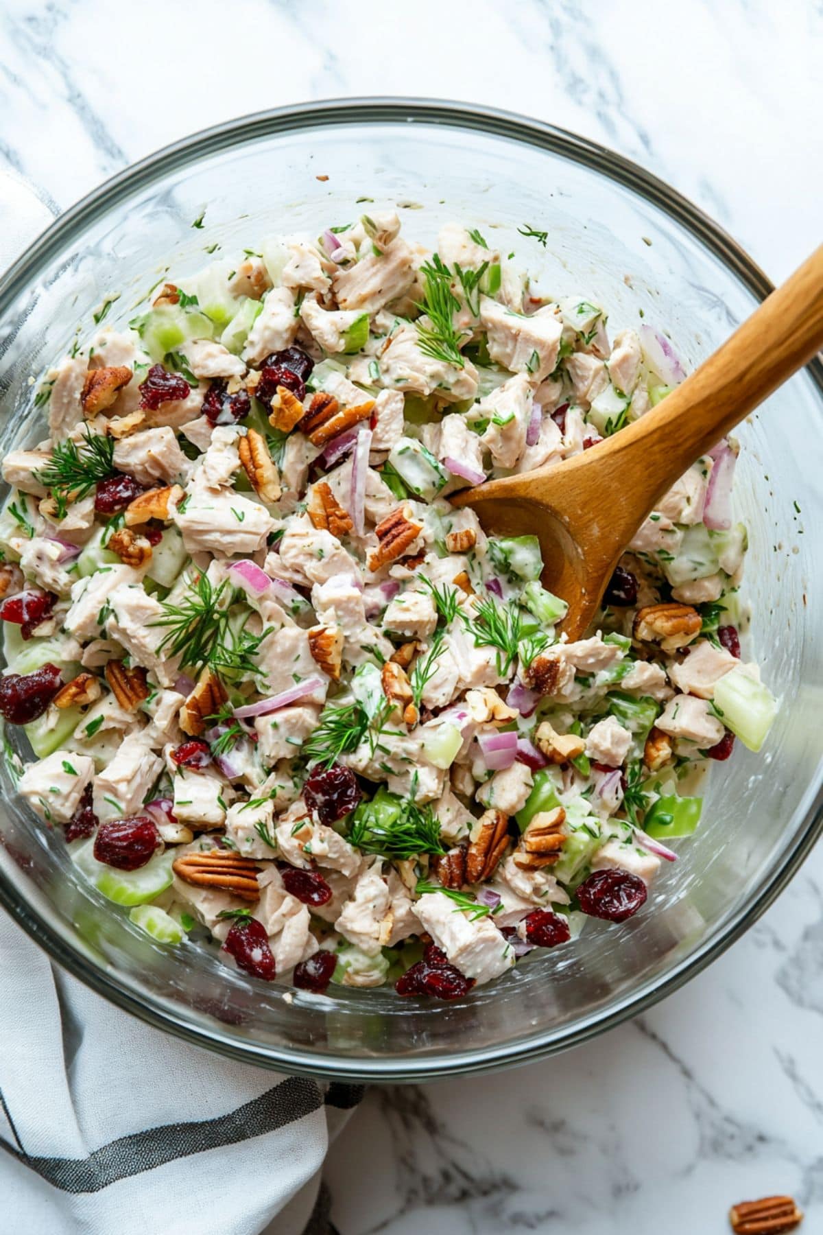 Turkey salad made with cube sliced turkey meat, cranberries, tossed in yogurt dressing in a glass mixing bowl.