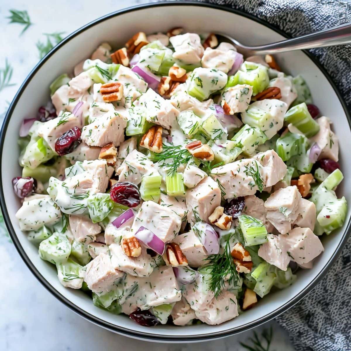 Turkey salad made with cube sliced turkey meat, cranberries, served in a white bowl.