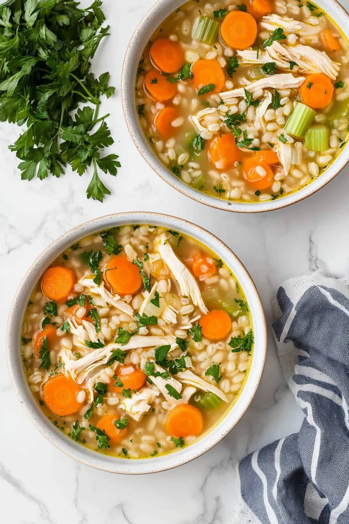 Two bowls of chicken barley soup with savory broth and colorful veggies.