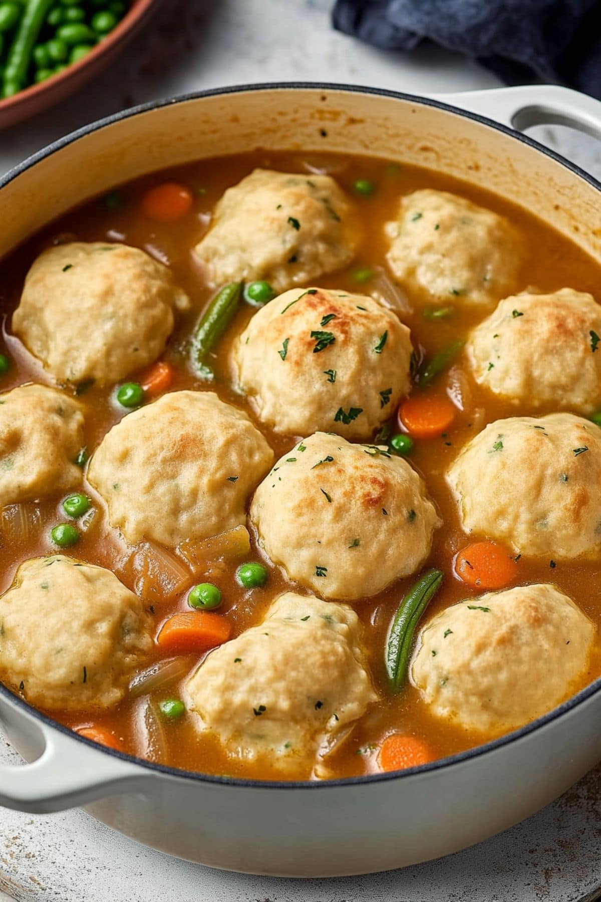 Vegetable stew with dumplings floating on top cooked in a Dutch oven pot.