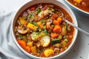 Vegetable stew served in a white bow with spoon on the side.