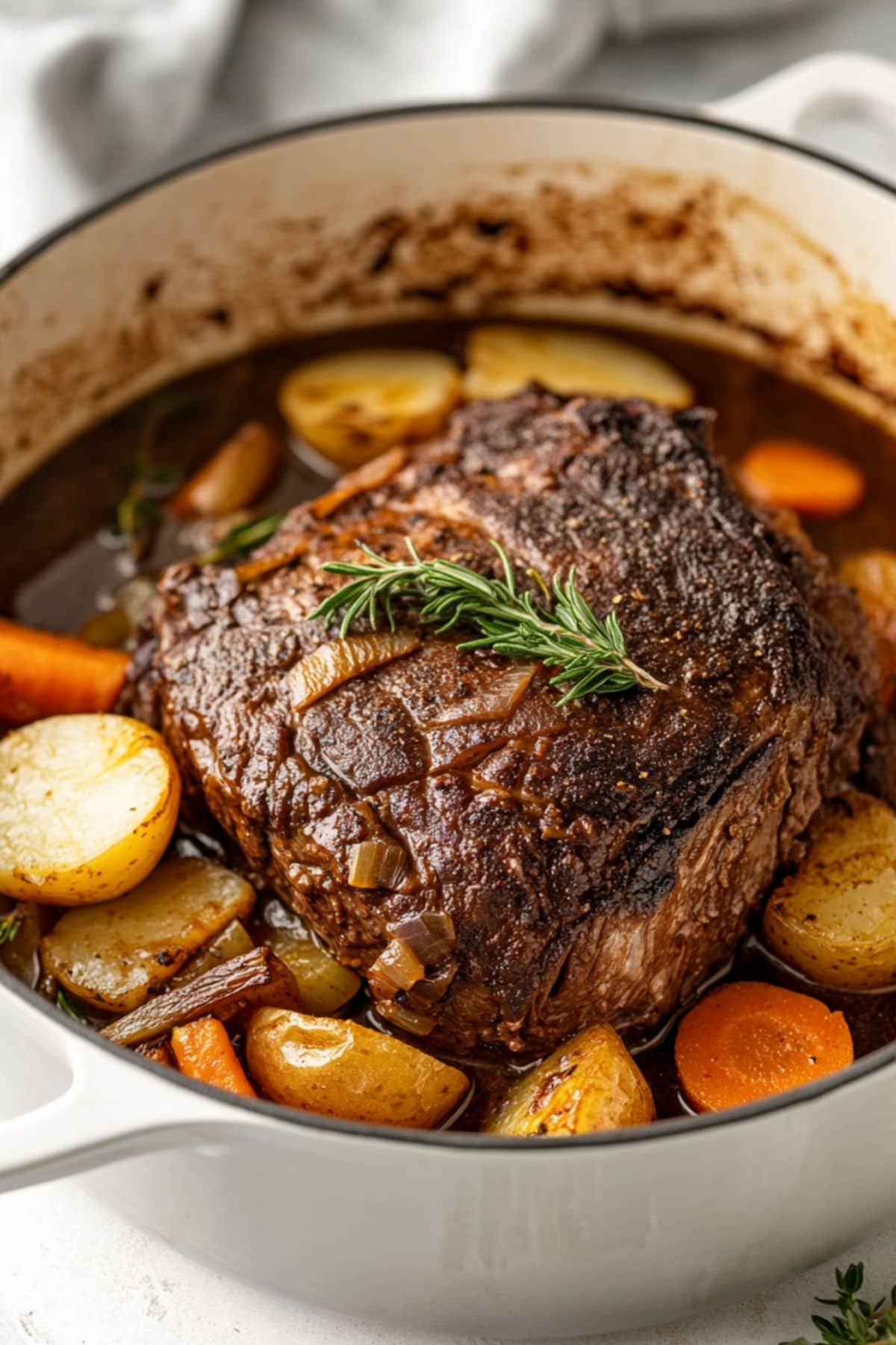 Pot roast cooked inside a Dutch oven with sauce, carrot and potatoes.