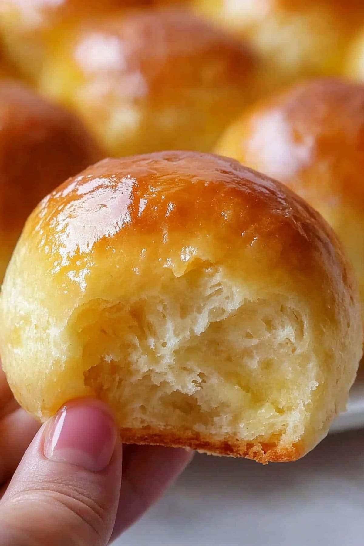 A hand holding a potato roll, close-up.