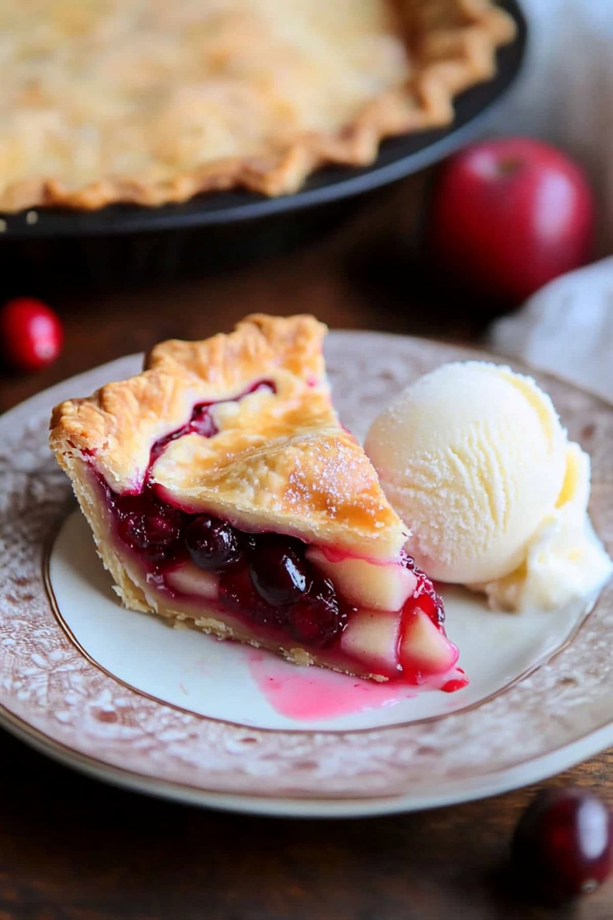 Homemade sliced apple cranberry pie with a scoop of ice cream.