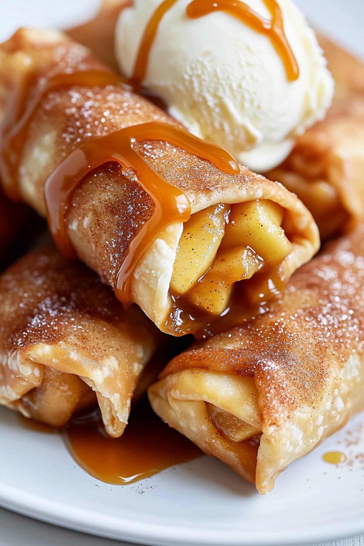 Apple Pie Egg Rolls Piled on a plate with caramel sauce and a scoop of ice cream