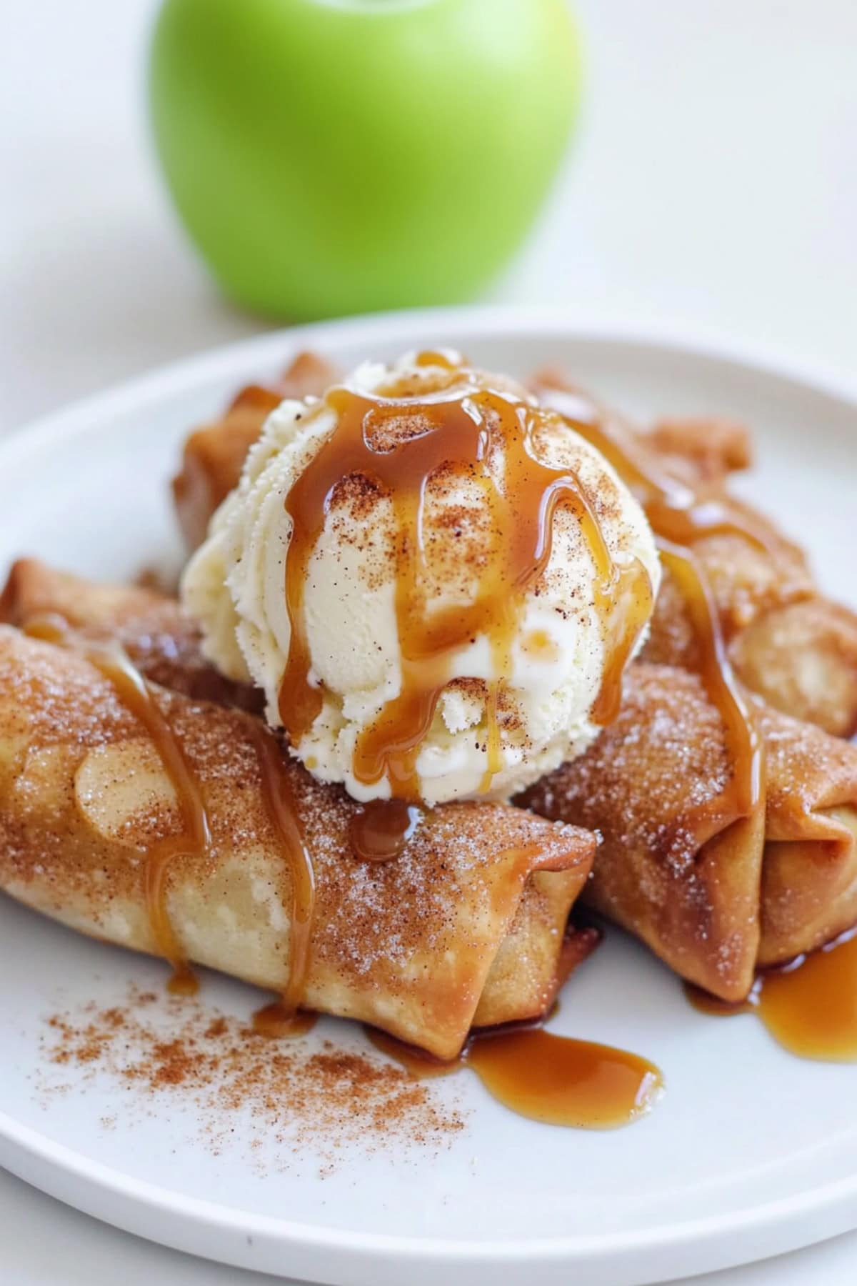 Apple Pie Egg Rolls on a plate with ice cream and caramel sauce