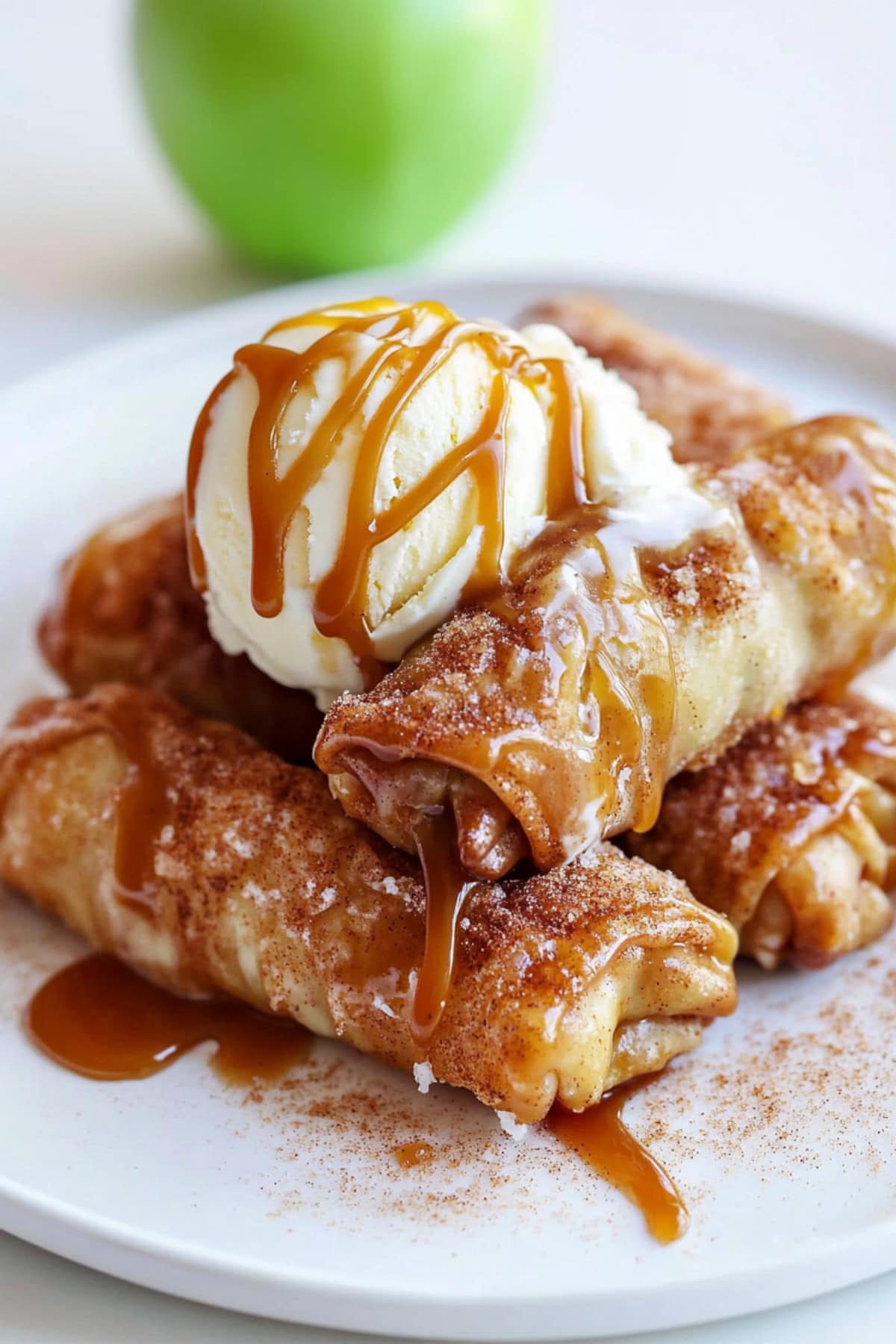 A stack of Apple Pie Egg Rolls with ice cream and caramel