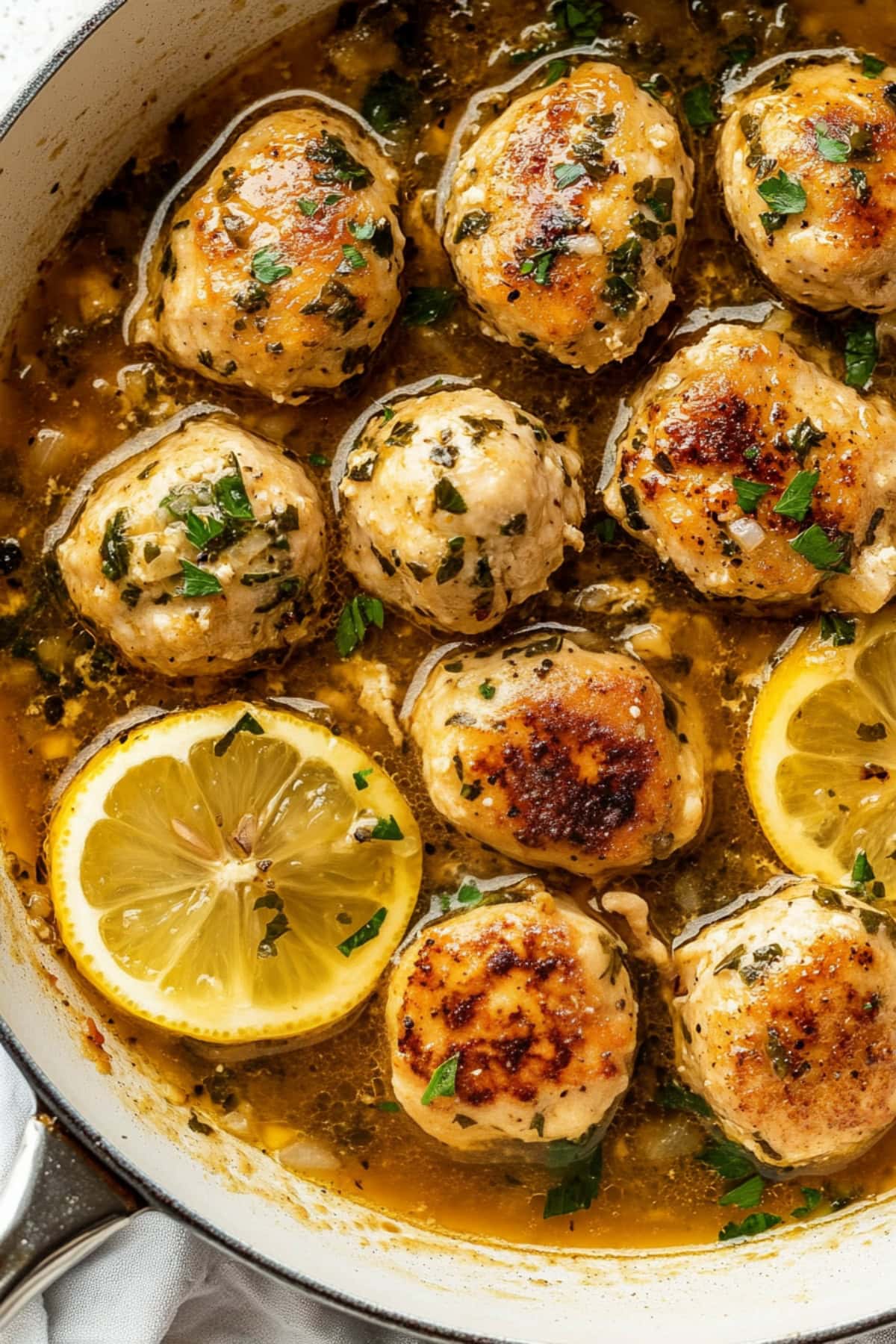 Chicken piccata meatballs with lemon in a large skillet.