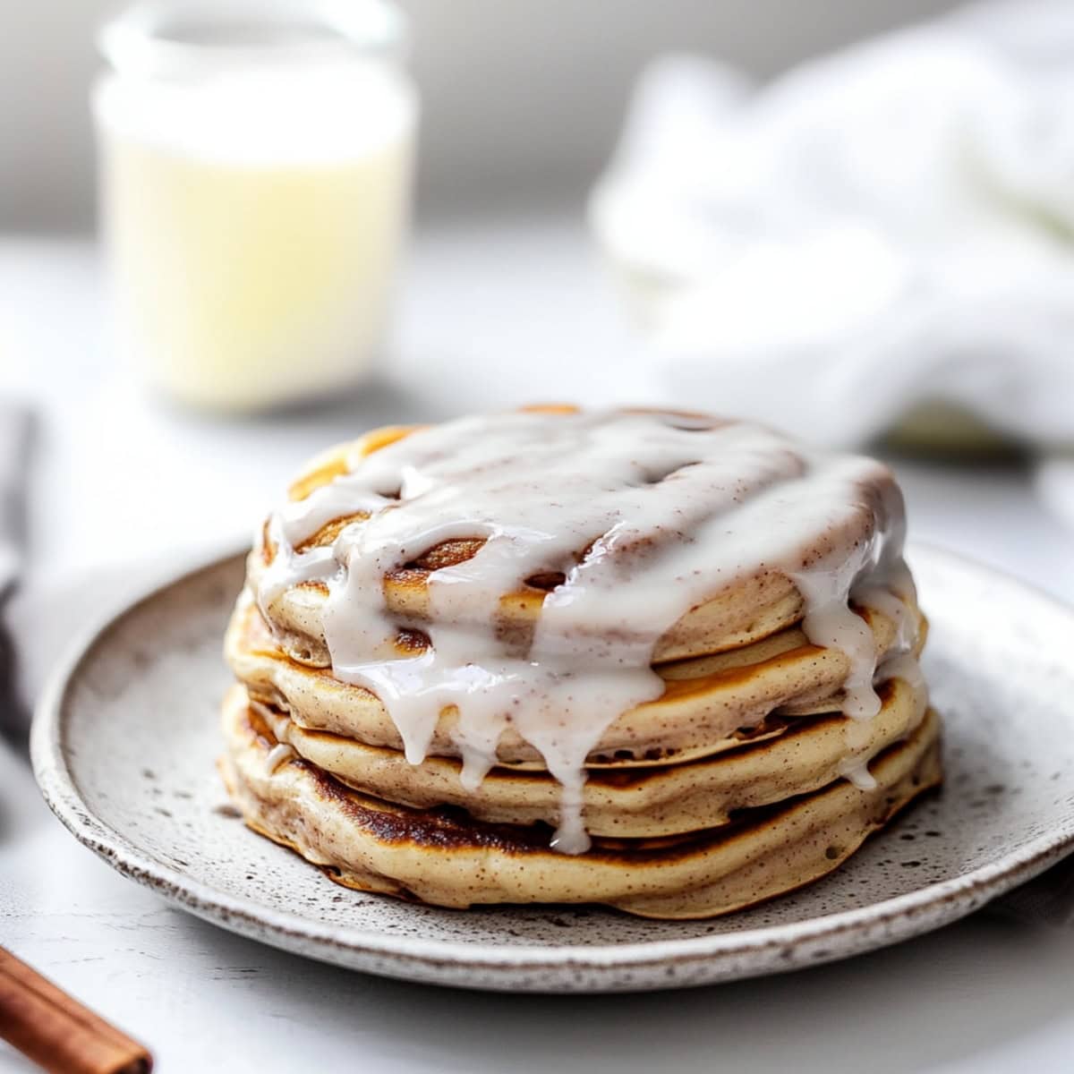 Cinnamon flavored pancakes stacked on a plate and drizzled with sweet glaze.