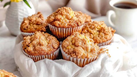 Bunch of cinnamon streusel muffins in a basket with cloth lining.