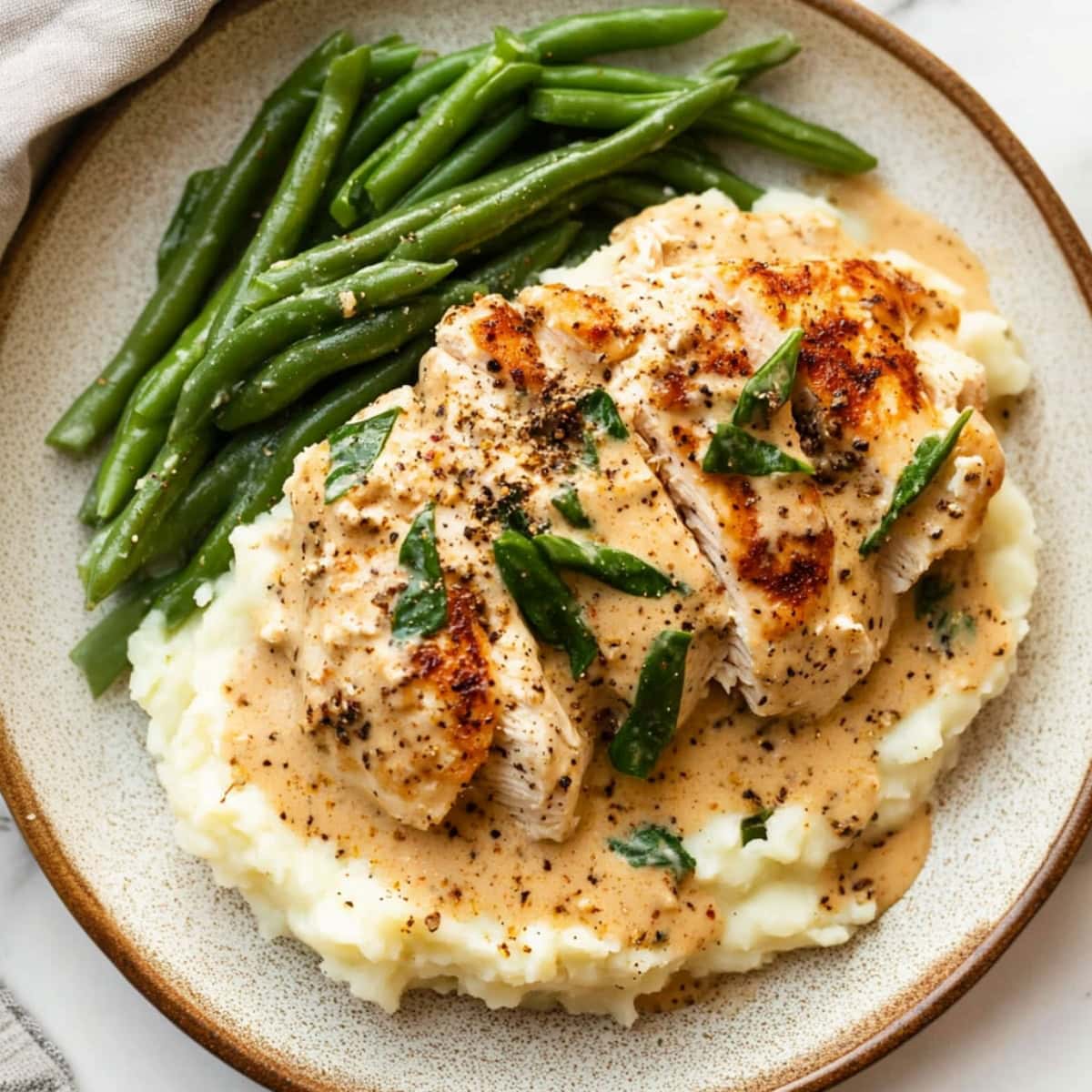 Mashed potatoes topped with sliced chicken breast with creamy cheesy sauce.