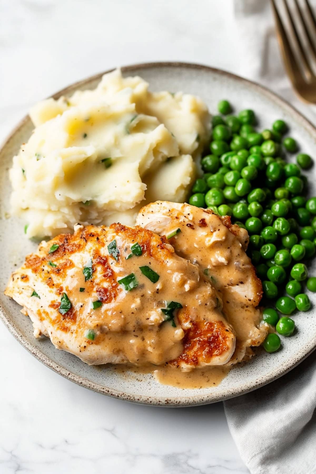 Creamy chicken boursin served with mashed potatoes and green peas in a plate.