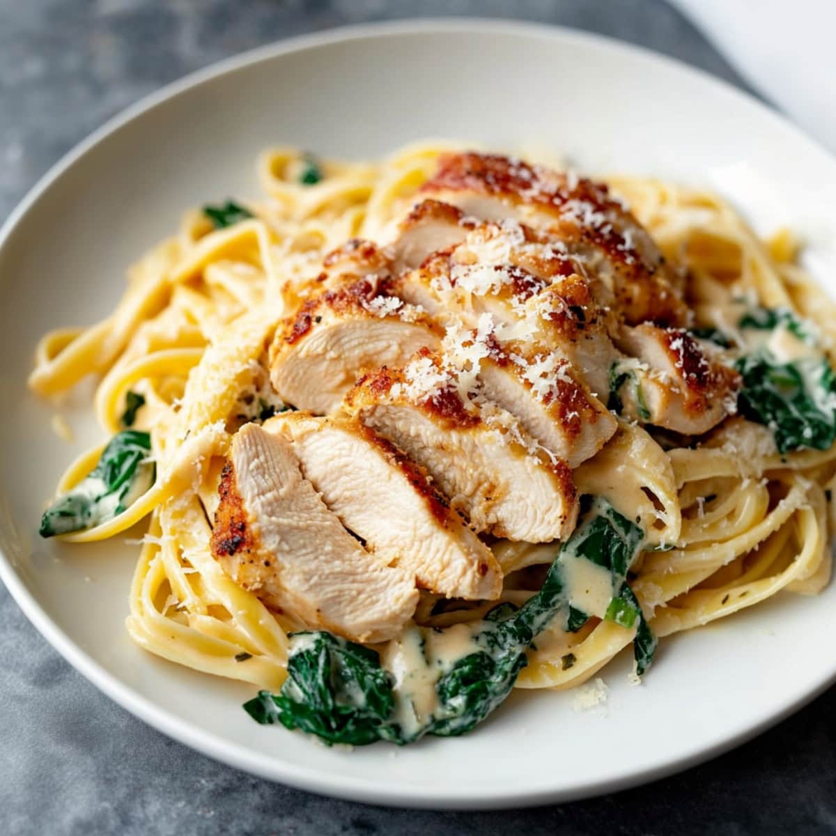 Pasta served with sliced chicken Florentine served in a white plate.