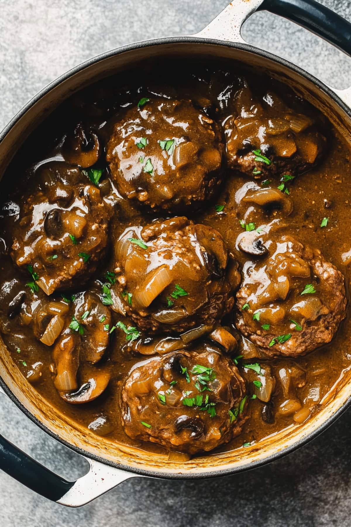 A pot of hamburger steak with onions, mushrooms and herbs.