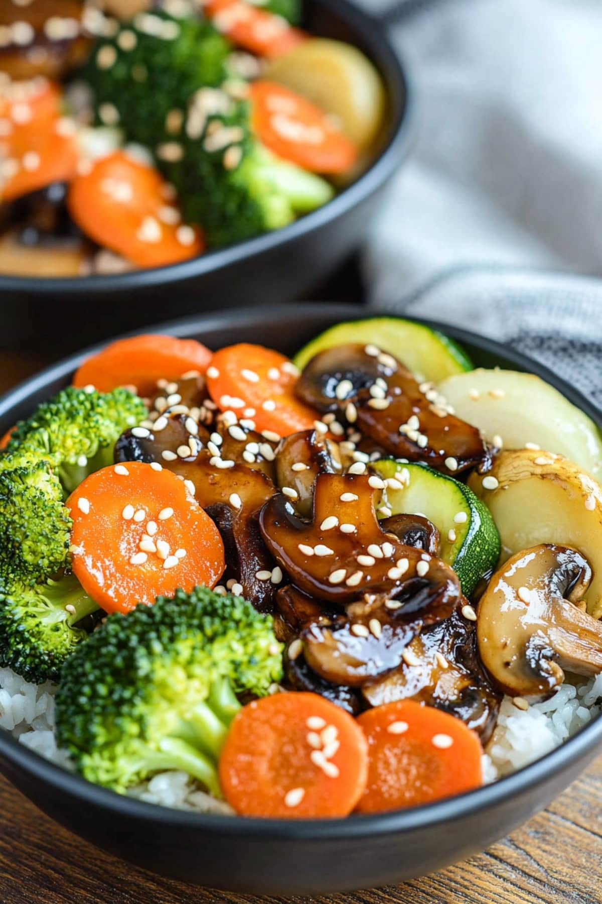 Hibachi vegetable served with white rice on black bowls. 