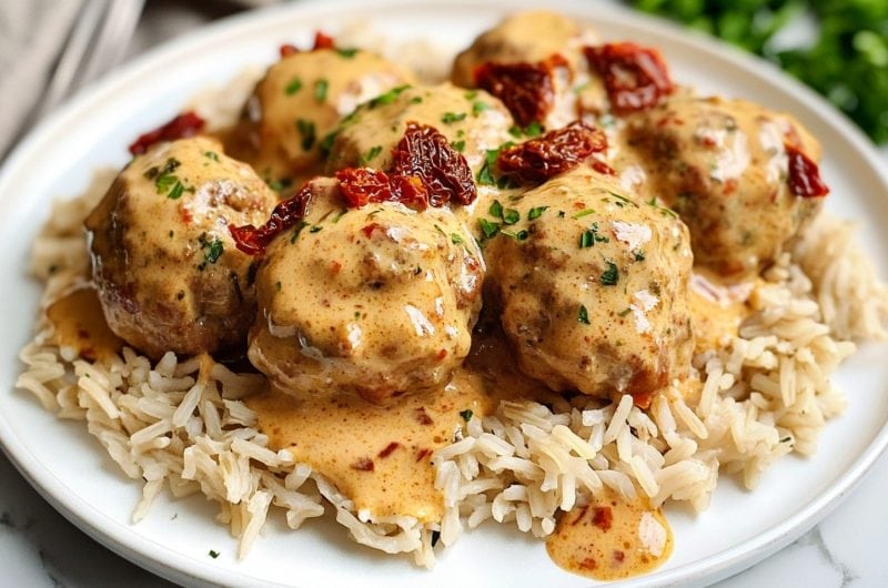 Marry me chicken meatballs served on top of rice in plate garnished with sun dried tomatoes.