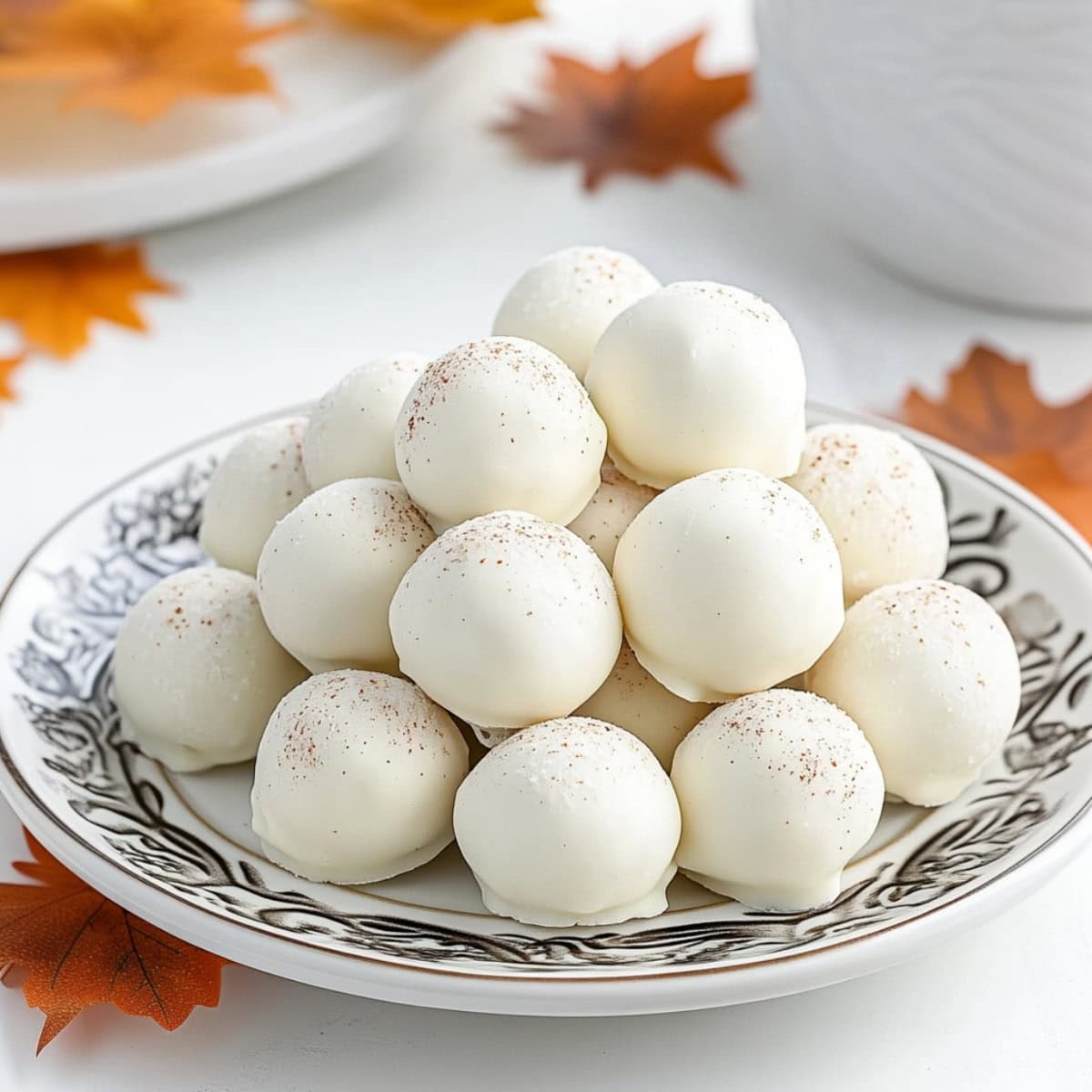 A stack of homemade no-bake pumpkin cheesecake truffles coated in white chocolate.