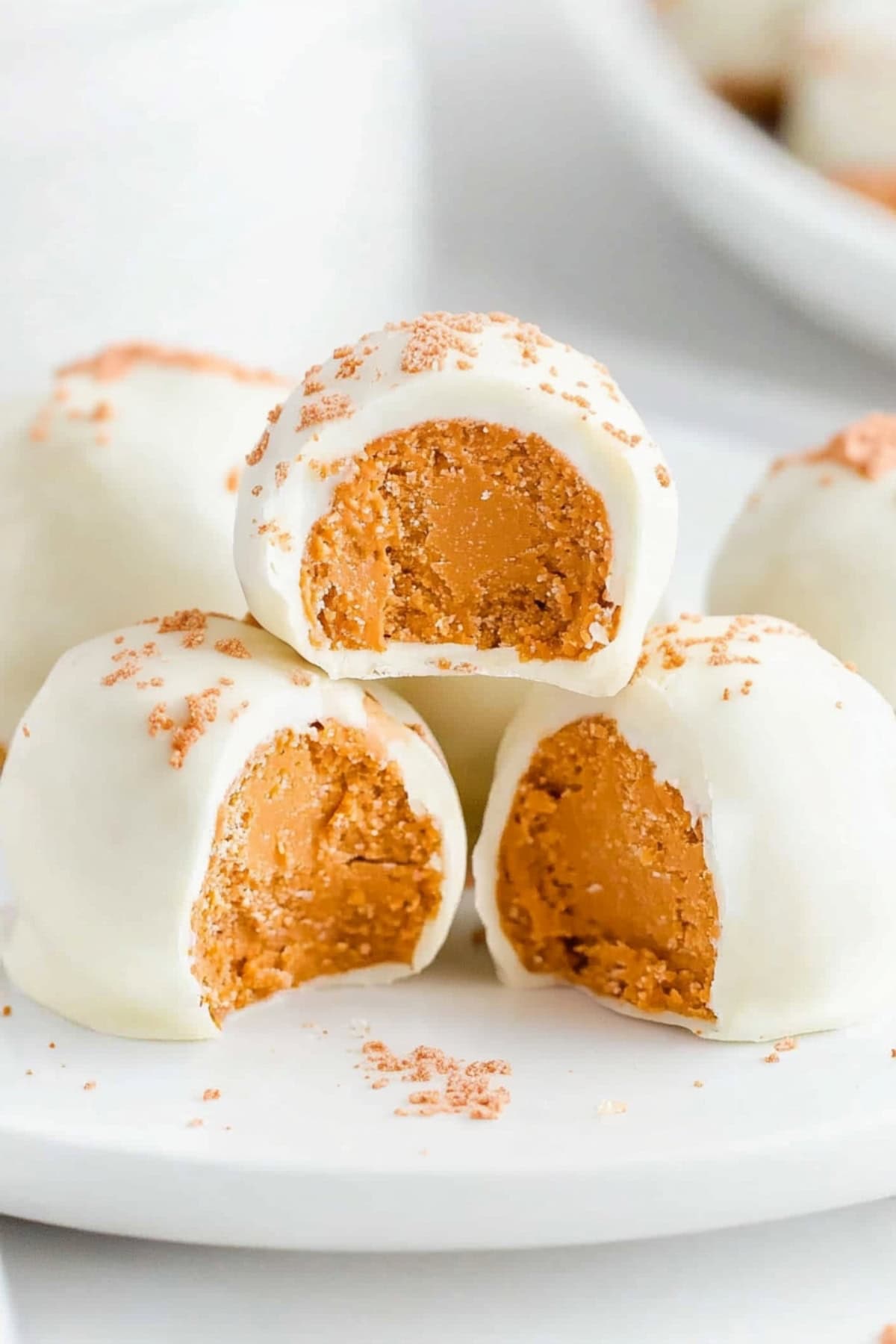 Homemade no-bake pumpkin cheesecake balls stacked on a plate, side view