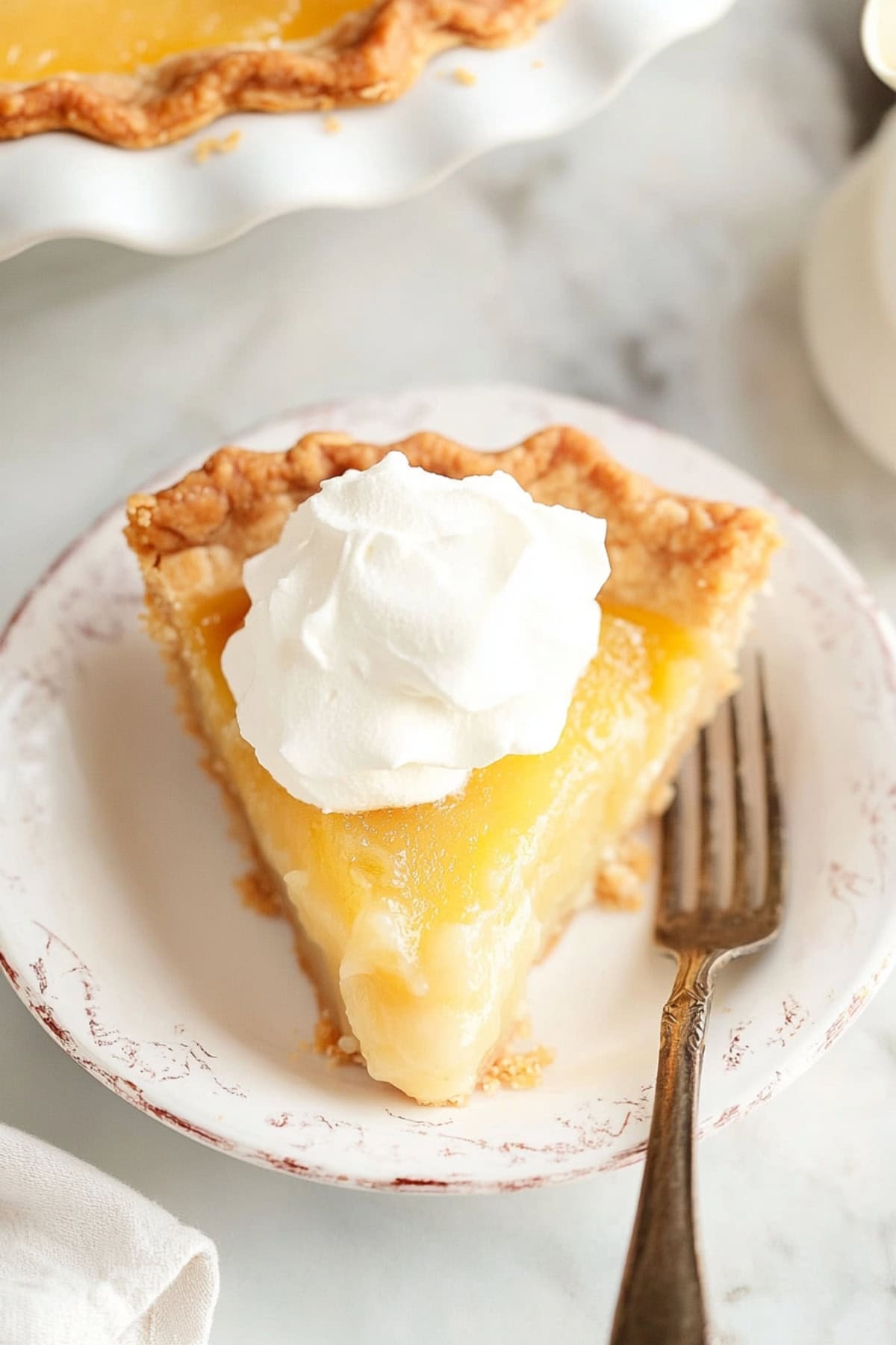 A slice of Old Fashioned Vinegar Pie on a plate with whipped cream