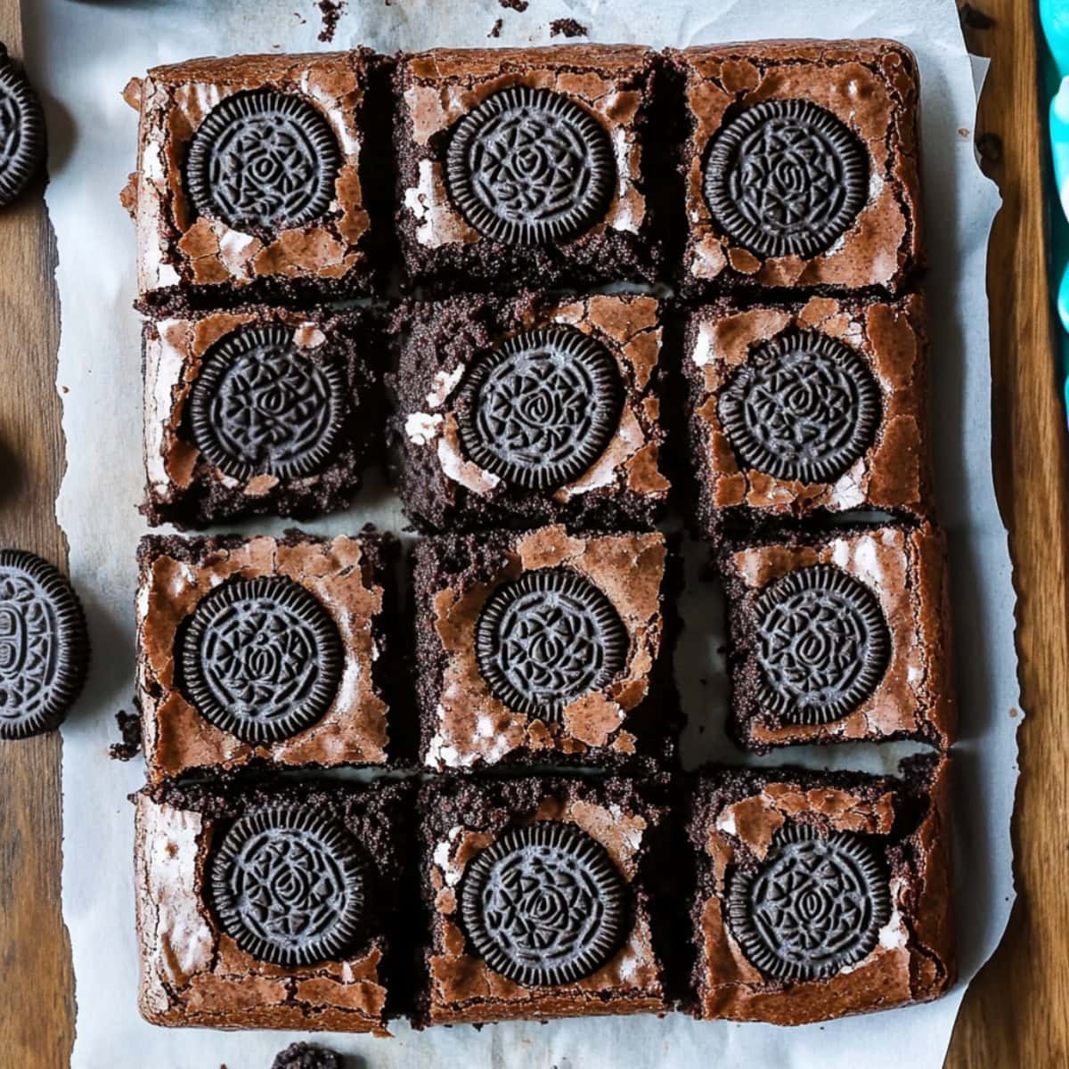 Oreo brownies cut into squares on a wooden board with parchment paper, top view