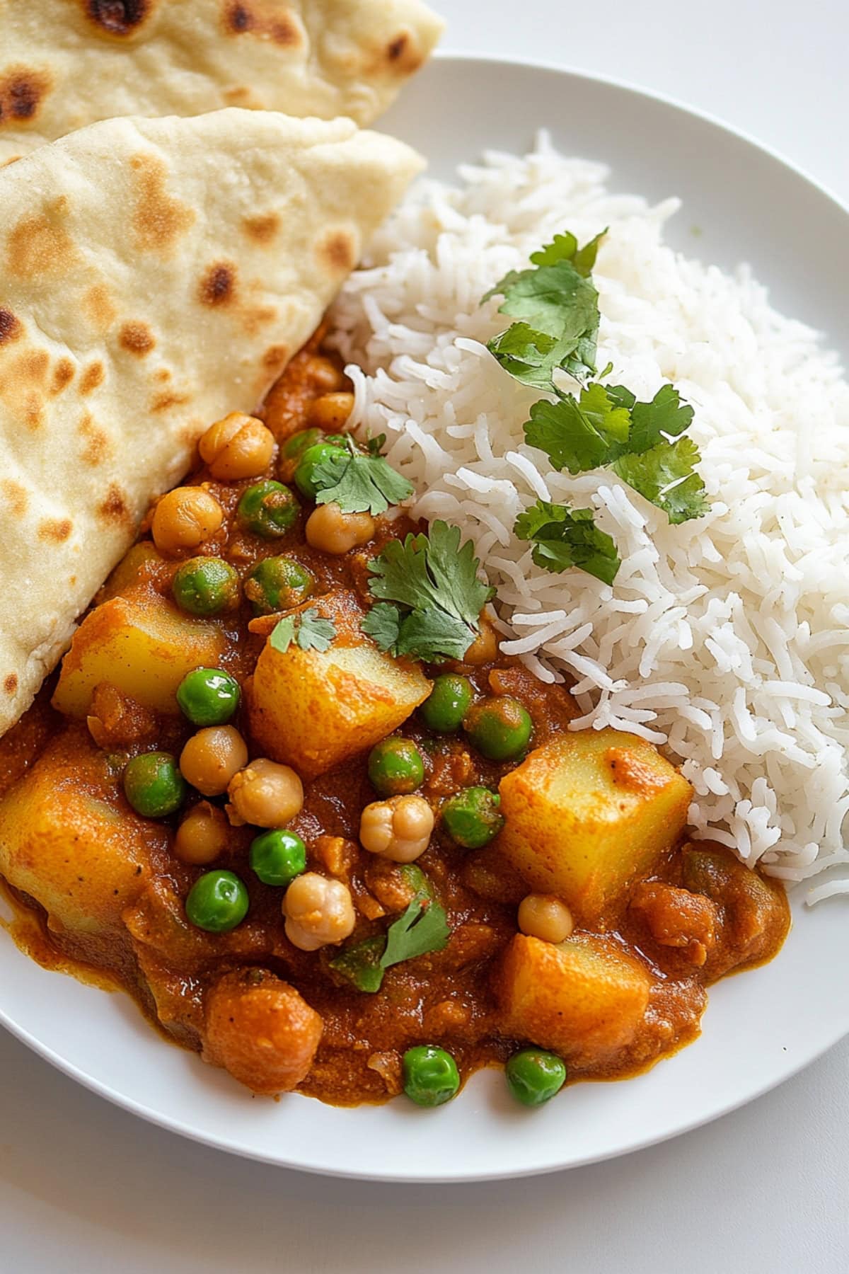 Potato curry served with rice and naan bread on a plate.