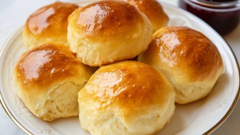 Fluffy potato rolls arranged neatly on a plate with a jar of jam.