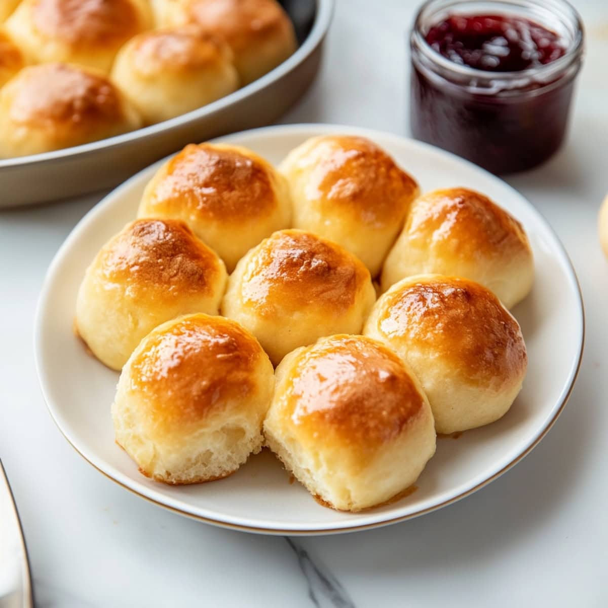 Close-up of freshly baked potato rolls with a shiny, buttery top served in a plate.