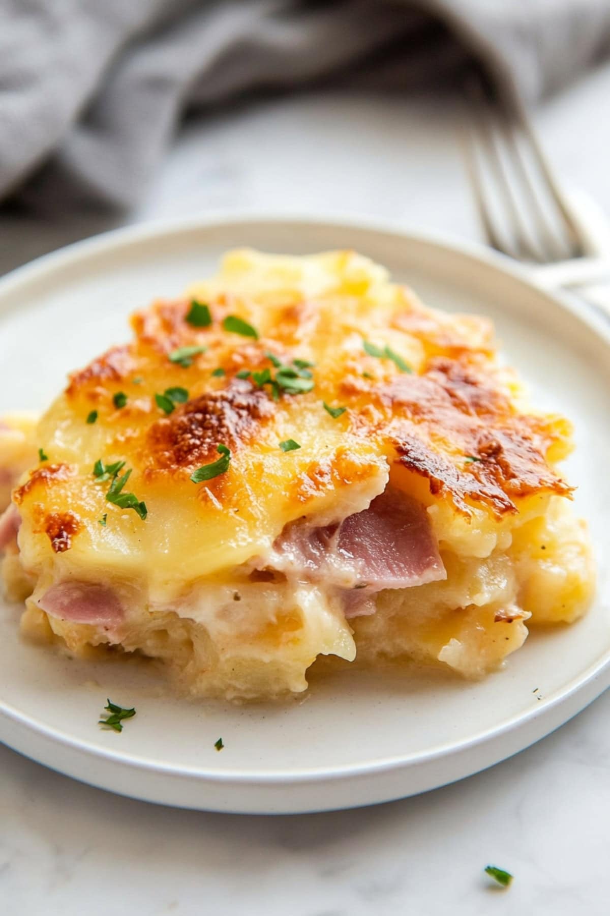 Golden-brown scalloped potatoes with tender slices of ham, baked to perfection and served hot from the oven.