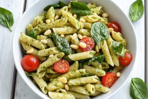 Pasta with pesto pasta, basil, tomatoes, cheese and pine nuts.