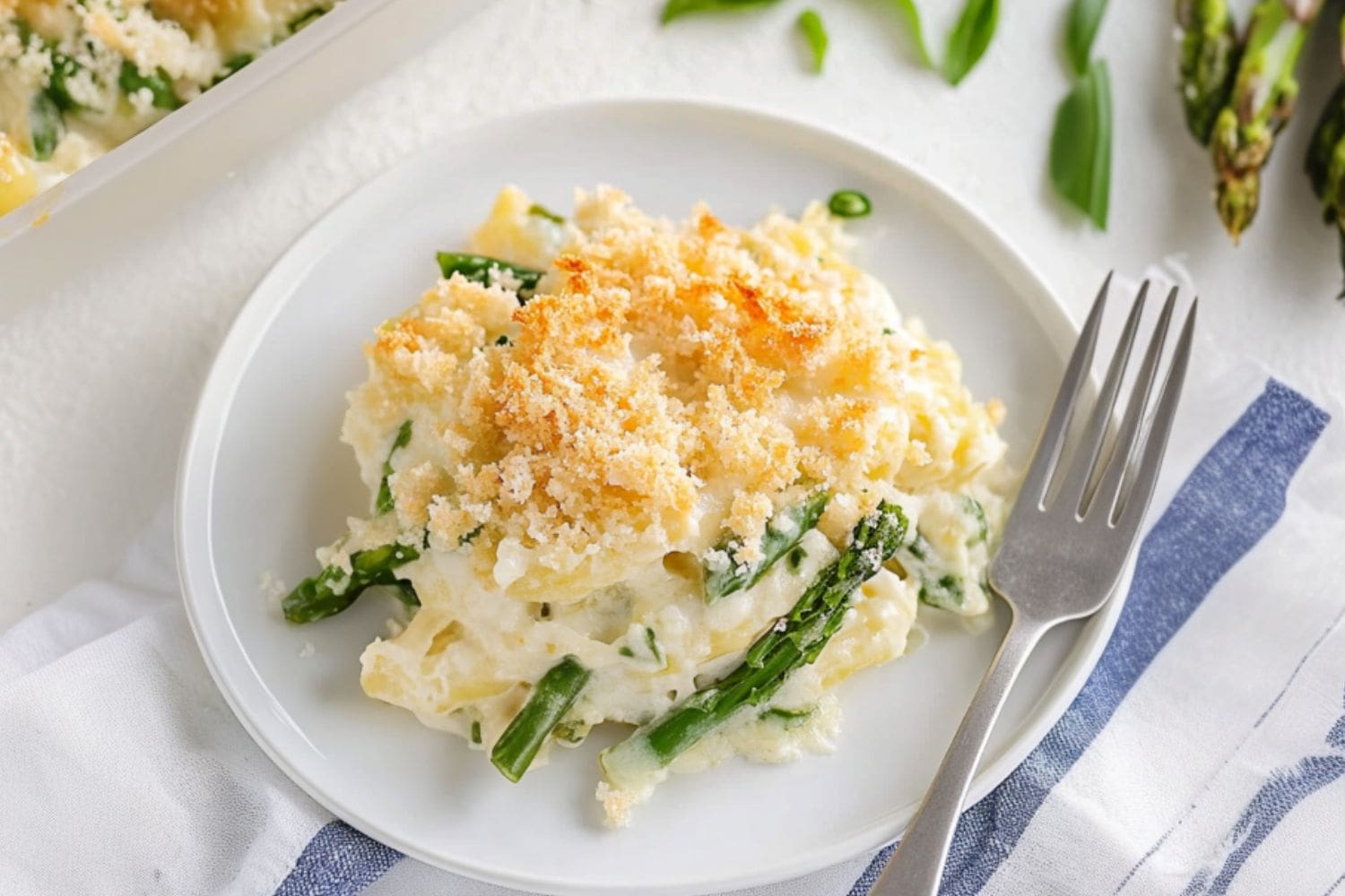 Asparagus casserole serving in a white plate, fork on the side.