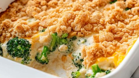 Cheesy and creamy broccoli casserole in a white baking dish covered with crushed Ritz crackers.